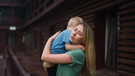 Mother-calms-down-upset-weepy-toddler-son-on-veranda-deck