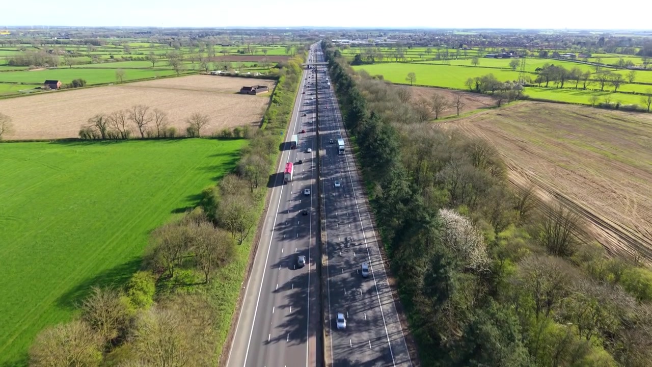 Prospettiva dall'alto di veicoli pendolari e camion merci su una strada a doppia carreggiata.