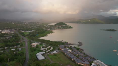 port airlie beach bay lagoon coral sea marina aerial drone road cars towards cannonvale sunrise morning rain shower heart of great barrier reef whitsundays whitehaven jetty yachts forward motion