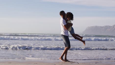 padre afroamericano y su hija jugando en la playa