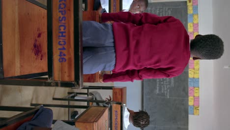 vertical shot of female teacher and children in african classroom