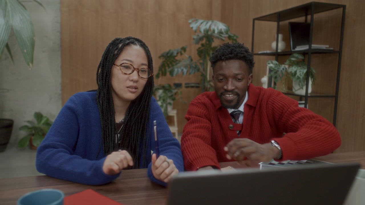 Diverse Colleagues Using Laptop, Smiling and Talking in Modern Office