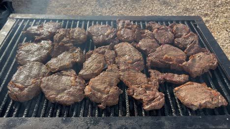 varios filetes de carne de res medianos y raros se cocinan en la parrilla sobre carbón caliente afuera