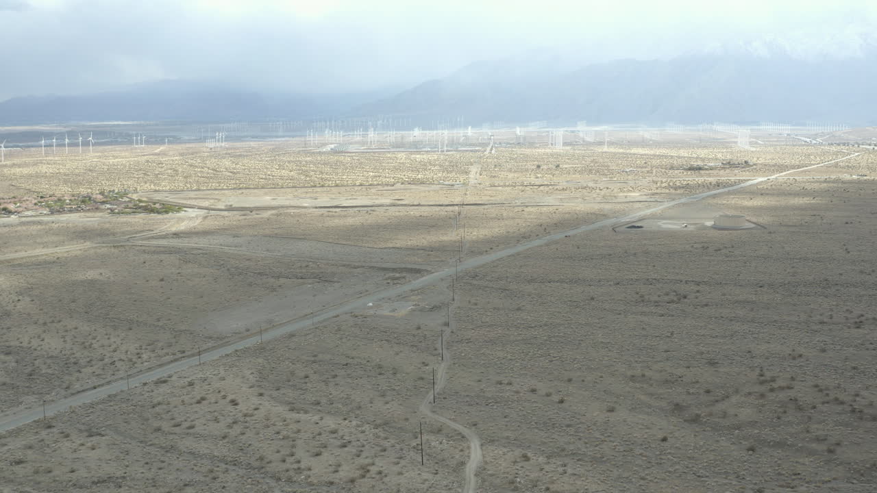 vuelo sobre una solitaria carretera desértica con molinos de viento en la distancia.
