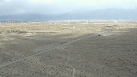 Flight-over-lonely-desert-road-with-windmills-in-the-distance