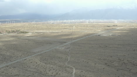 flight over lonely desert road with windmills in the distance