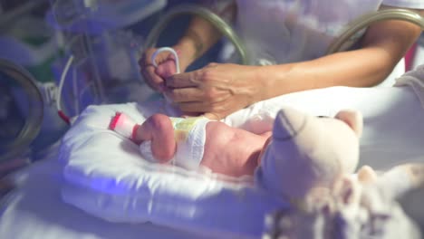Krankenschwester-Klebt-Sicherheitsetikett-An-Zerbrechlichem-Neugeborenen-An