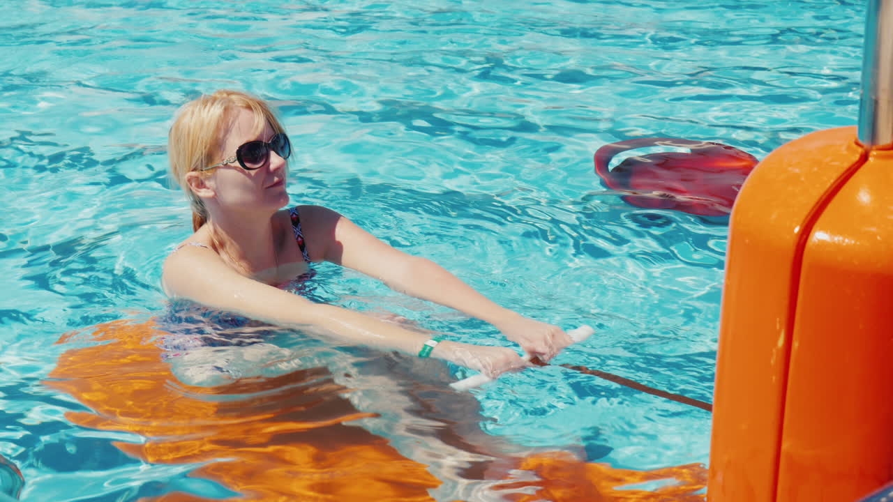 Young Woman Exercising In The Pool Outdoors In The Resort