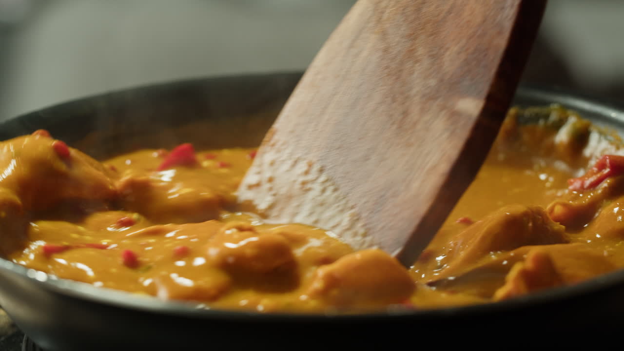 Yellow boiling sauce on pan close-up. Asian cuisine concept. Curry is a dish with a sauce seasoned with spices. Curries may contain fish, meat, poultry, or shellfish, either alone or in combination with vegetables. Others are vegetarian.