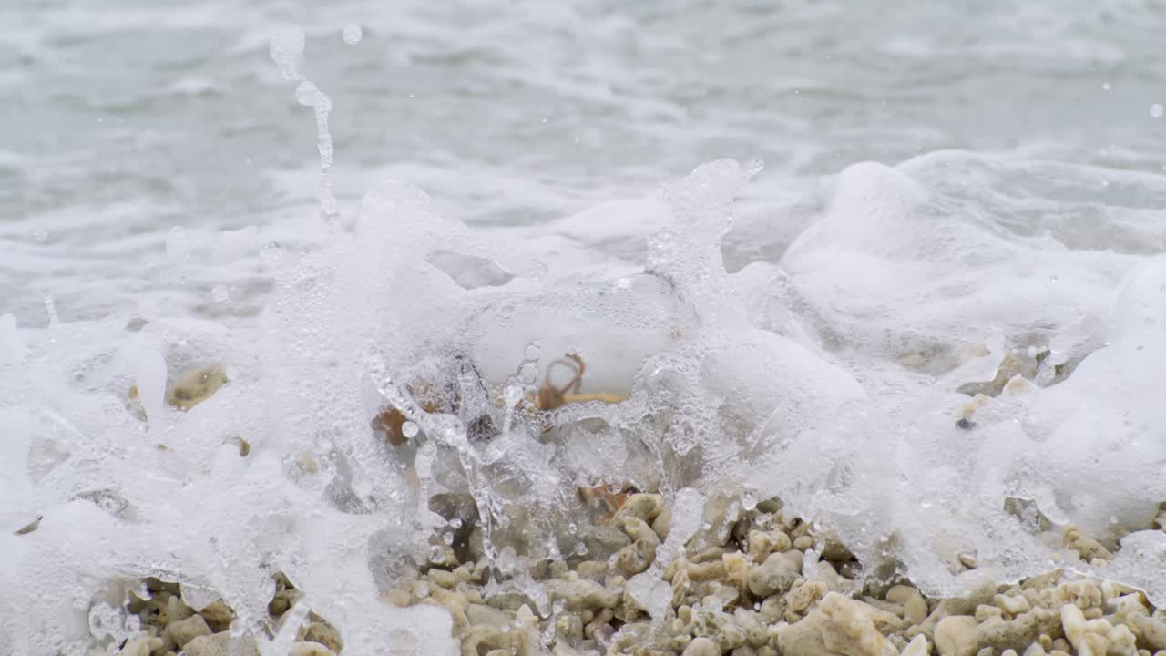 Mensaje en una botella en una playa de arena. Grabado con una cámara superlenta a 1000 FPS