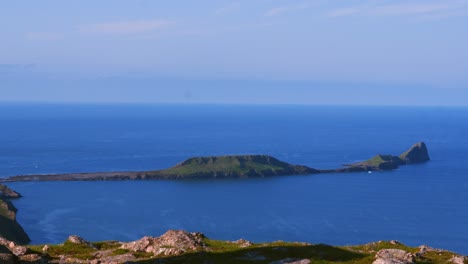 pan from moorland peak marker on rhossili downs to worm's head landmark with rocky cliffs in gower peninsula, wales, uk. adventure, holiday concept 4k