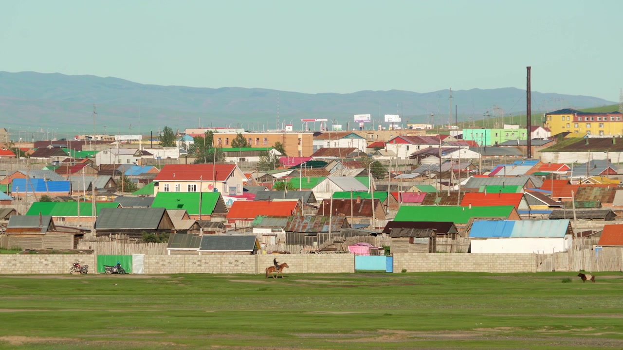 Ratsastaja pienen värikkään kylän lähellä Mongoliassa