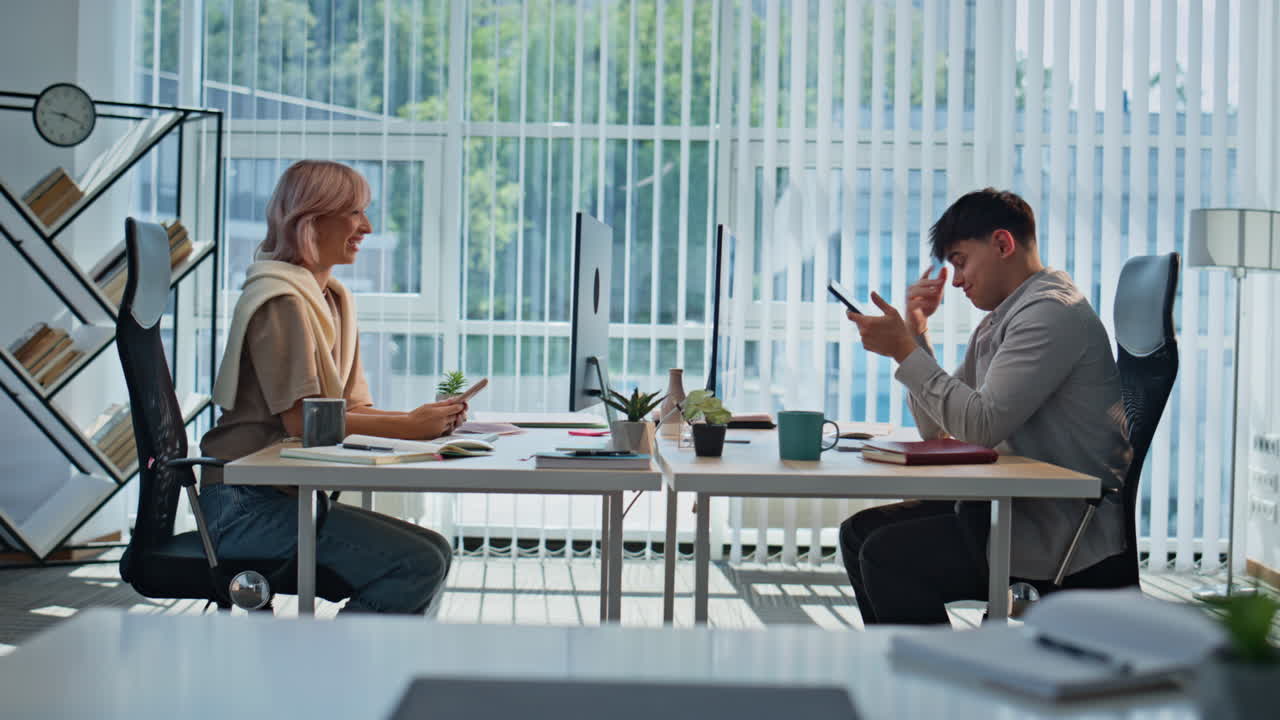 Positive managers looking telephones resting at office. Coworkers taking break