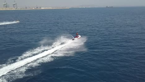 tiro de seguimiento de dos chicos corriendo juntos en moto de agua en el mar azul, chipre