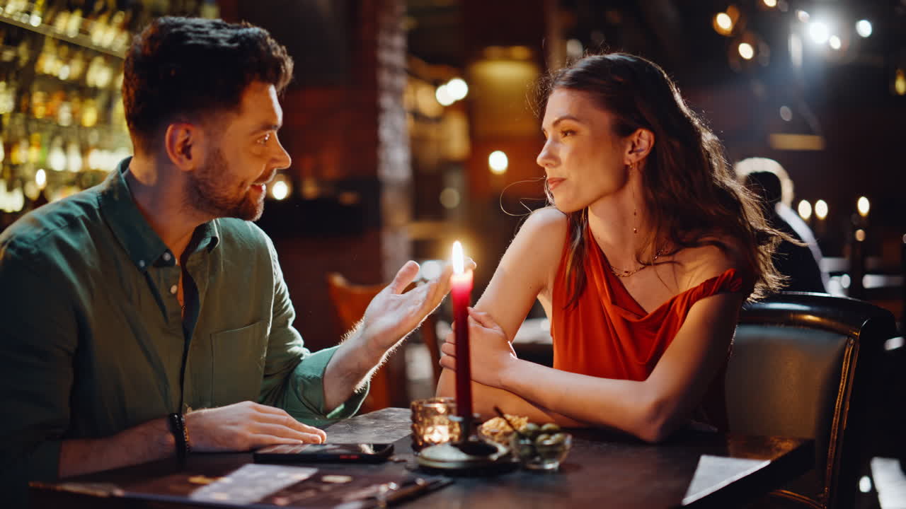 Primo piano di una coppia romantica che si gode una conversazione in un pub buio. Coppia sorridente che flirta