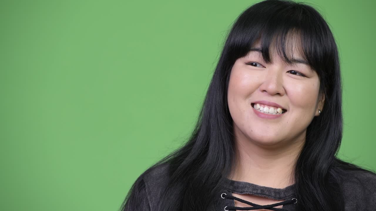 Beautiful overweight Asian woman smiling and thinking