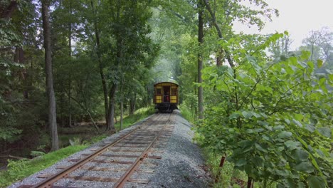 A-View-of-An-Antique-Steam-Engine,-Leaving-and-Going-Down-the-Single-Track-in-the-Woods-on-a-Sunny-Day