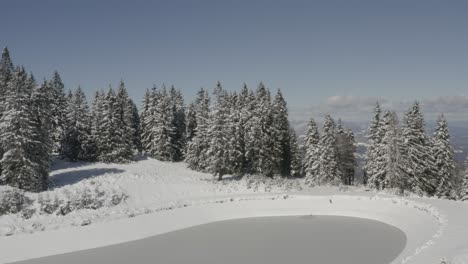 rain water catchment lake at kope ski resort in slovenia during winter, aerial orbit around shot