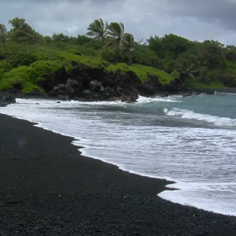 Las-Olas-Ruedan-Hacia-Una-Playa-De-Arena-Negra-En-Hawaii