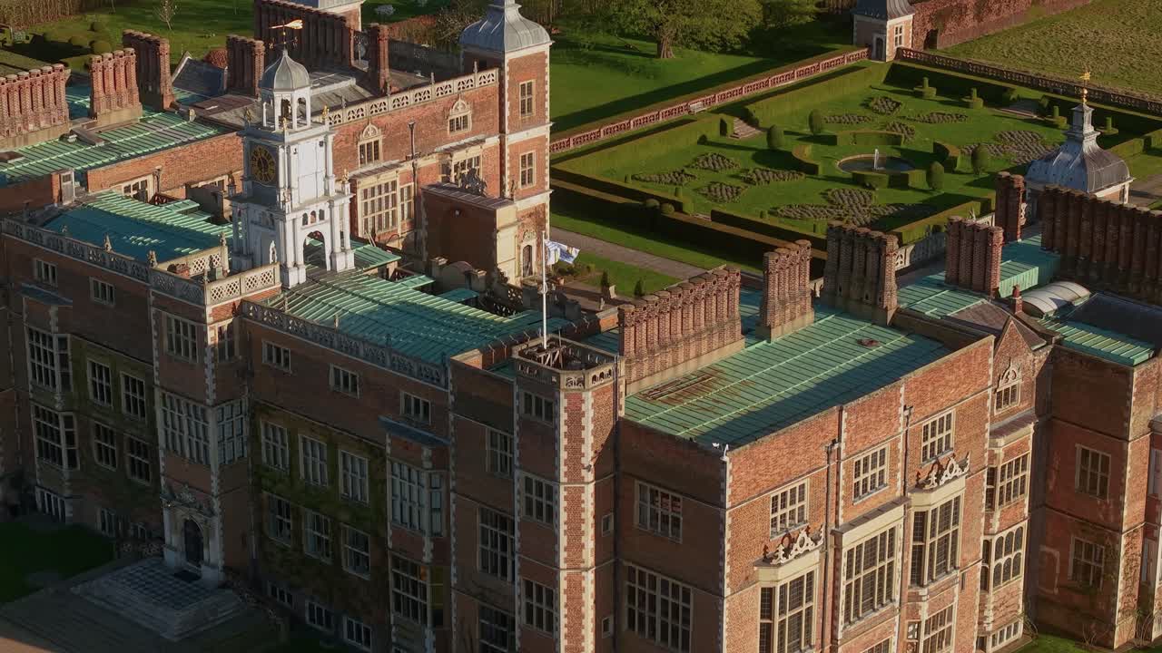 Aerial view overlooking flag waving on the corner of Hatfield country house rooftop in the UK