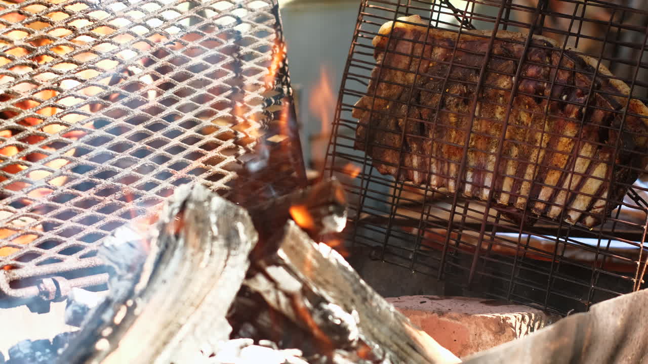 Upright lamb rib being grilled next to flaming wood fire, South African culture