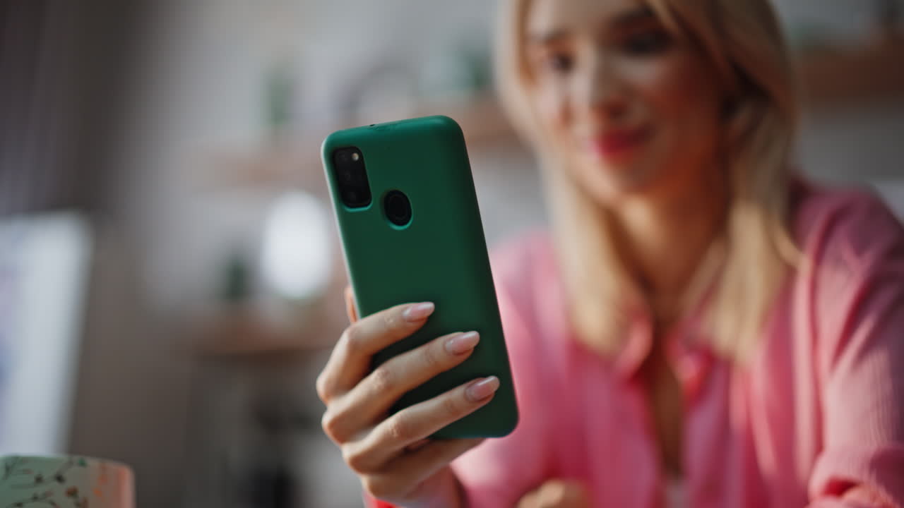 Blonde lady shopping online smartphone choosing goods alone at kitchen closeup