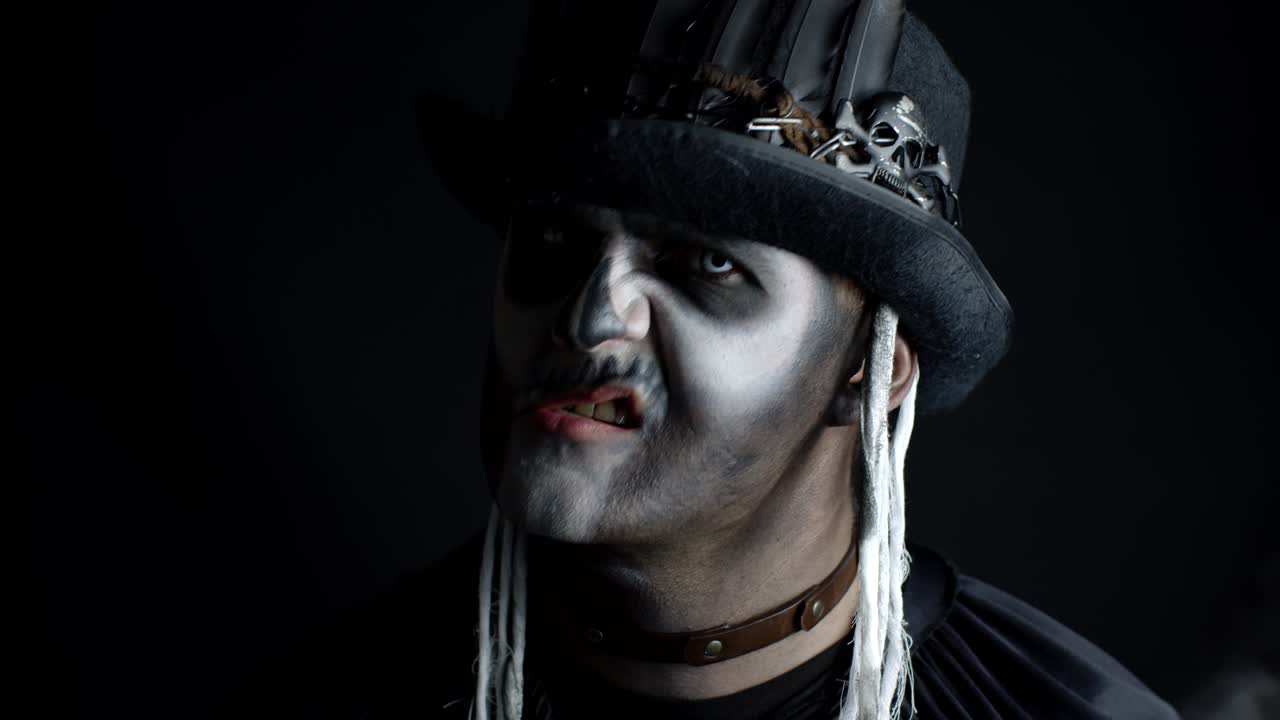 hombre siniestro con maquillaje de esqueleto que aparece de la oscuridad cuando la luz cae sobre él, haciendo caras