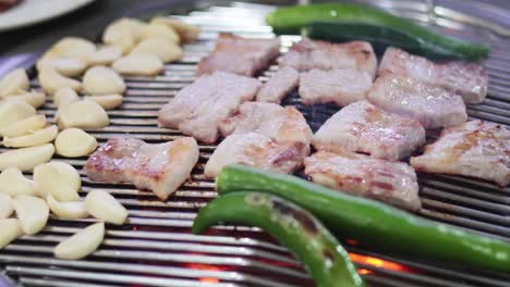 cooking pork belly on a grill with garlic and peppers