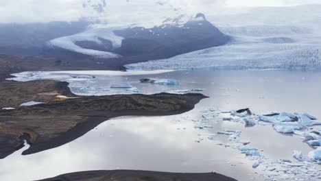 laguna glacial con icebergs paridos y glaciar en retirada distante, impacto del calentamiento global en el ártico, aéreo