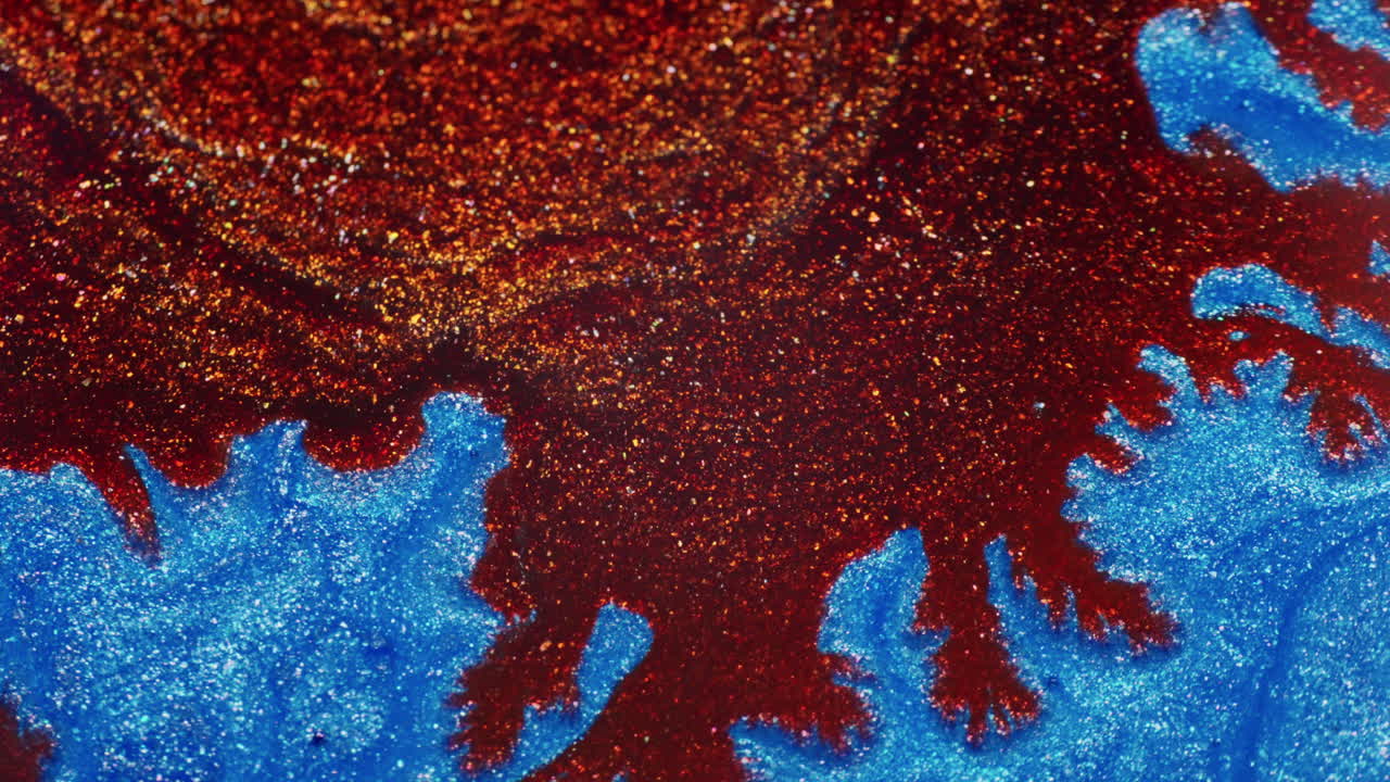 Macro shot of sparkling brown-gold pigment spreading through vibrant blue ink. Fluid shimmer and intricate texture