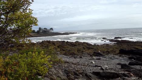 waves breaking on rocks and beach with house on point