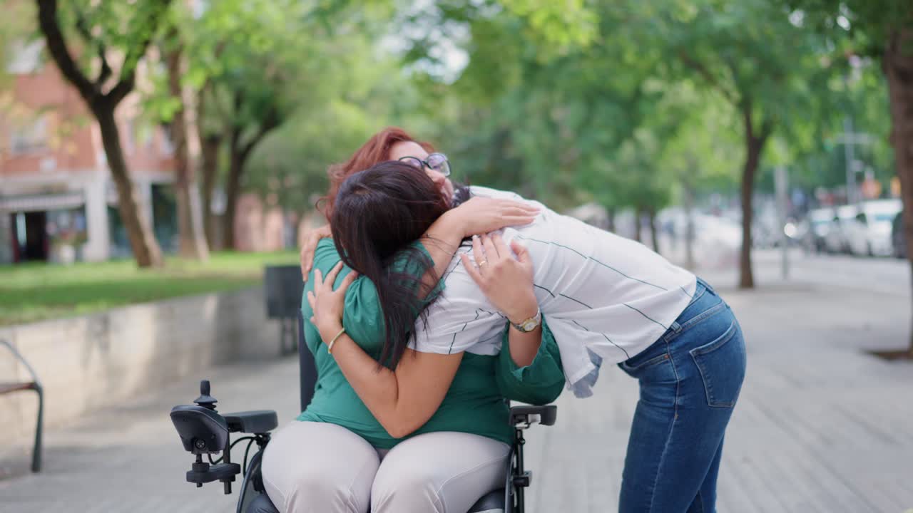 Woman in wheelchair hugging a friend in a park