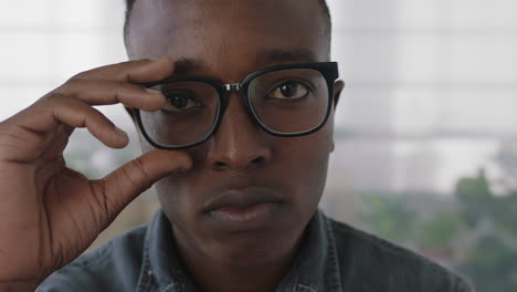 retrato en primer plano de un joven estudiante de negocios afroamericano. un pasante se quita las gafas mirando seriamente a la cámara.