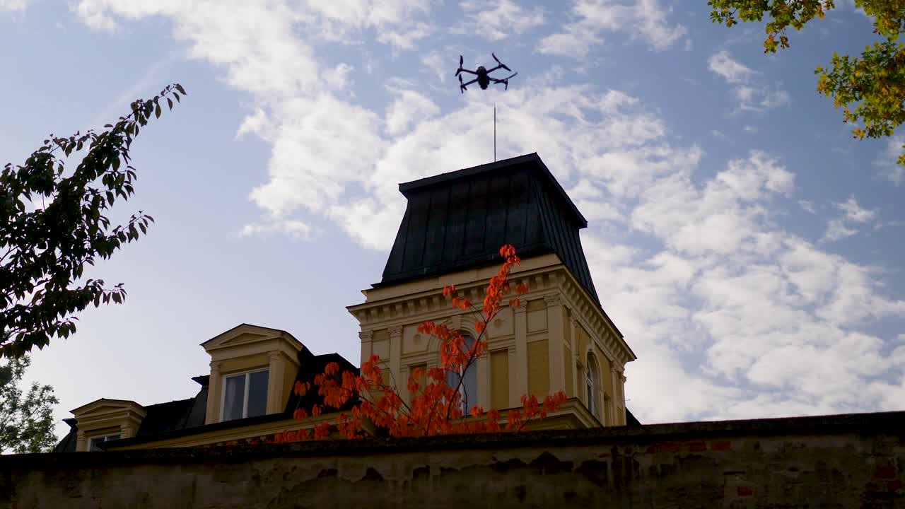 Silhouette of a drone flying and recording a building