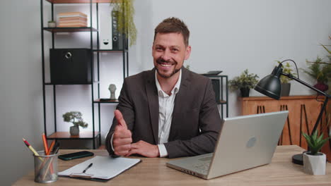 hombre de negocios feliz mirando con aprobación a la cámara mostrando los pulgares hacia arriba, como un signo positivo, buenas noticias