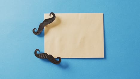 video de dos bigotes falsos y un sobre amarillo sobre un fondo azul.