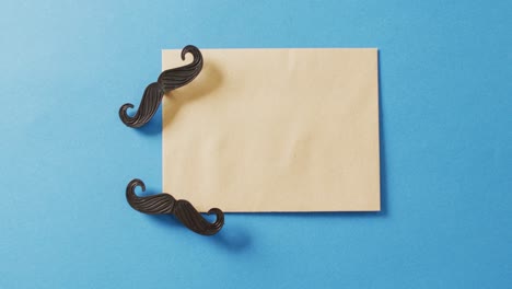 video of two false moustaches and yellow envelope on blue background