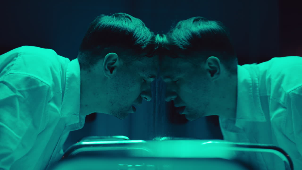 Man Looking at His Reflection in a Neon Green Light