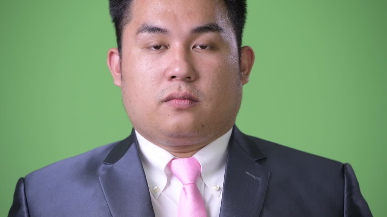 초록색 배경에 젊은 잘생긴 과체중 아시아 사업가