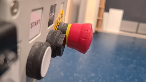 persona presionando el botón rojo de parada de equipo industrial, primer plano
