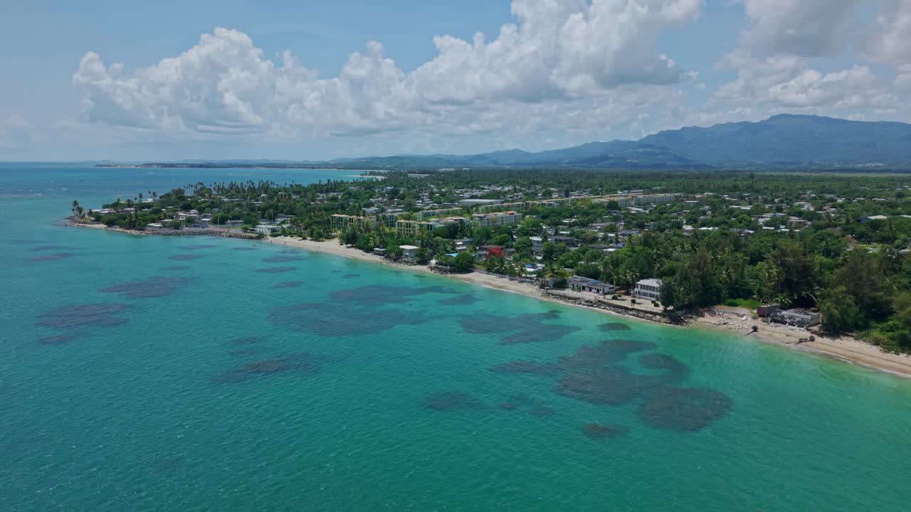 Establishing drone shot of Loiza cityscape with sand beach, Atlantic Ocean and blue sky during the day in Puerto Rico, USA