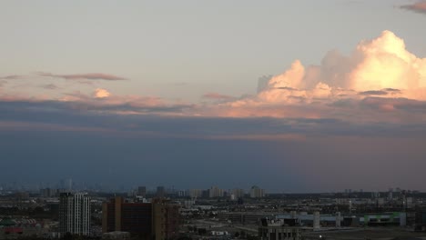 cloudscape time lapse view of white fluffy clouds moving in the wind over a city skyline, at sunset