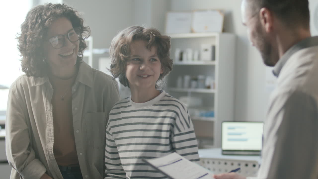 웃는 소년과 어머니는 친절한 의사와 건강 상담을 하고 있습니다.