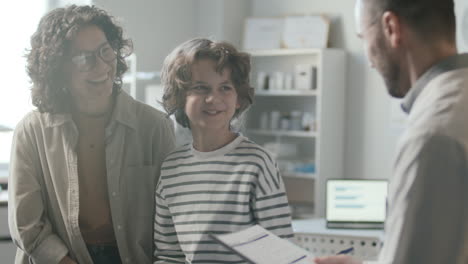 niño sonriente y madre teniendo consulta de salud con un médico amistoso