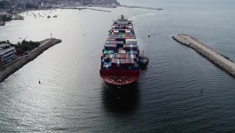 aerial view in front of a large bulk carrier, arriving at the port of manzanillo seaport - reverse, tilt, drone shot