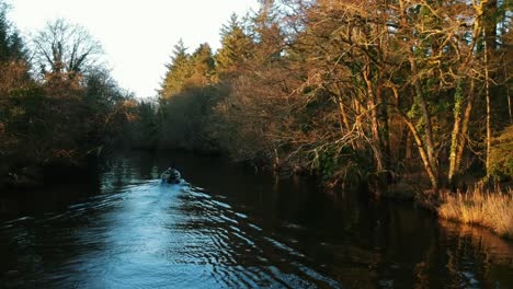 Toma-Aérea-Del-Barco-Del-Lago-Que-Viaja-Río-Abajo-En-Otoño