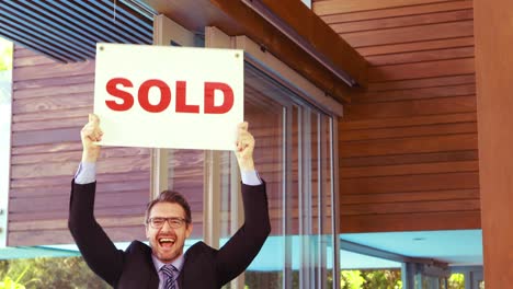 estate agent cheering and holding sold sign