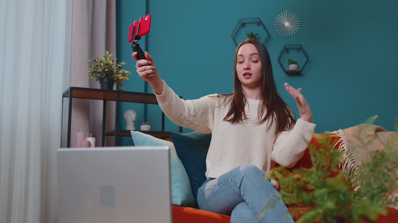 Girl blogger influencer taking selfie on smartphone make virtual social media video online at home