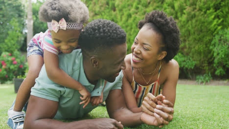 happy african american couple with two daughters playing in garden