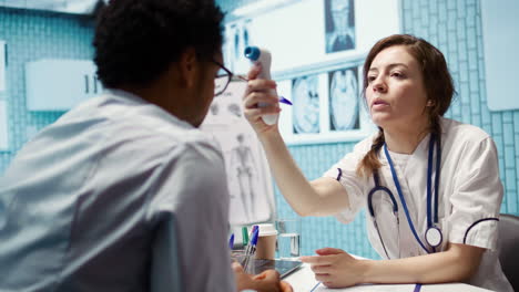 specialist uses a digital thermometer to check for fever and other flu symptoms